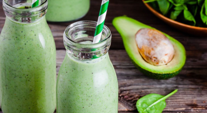 Green smoothies next to an avocado