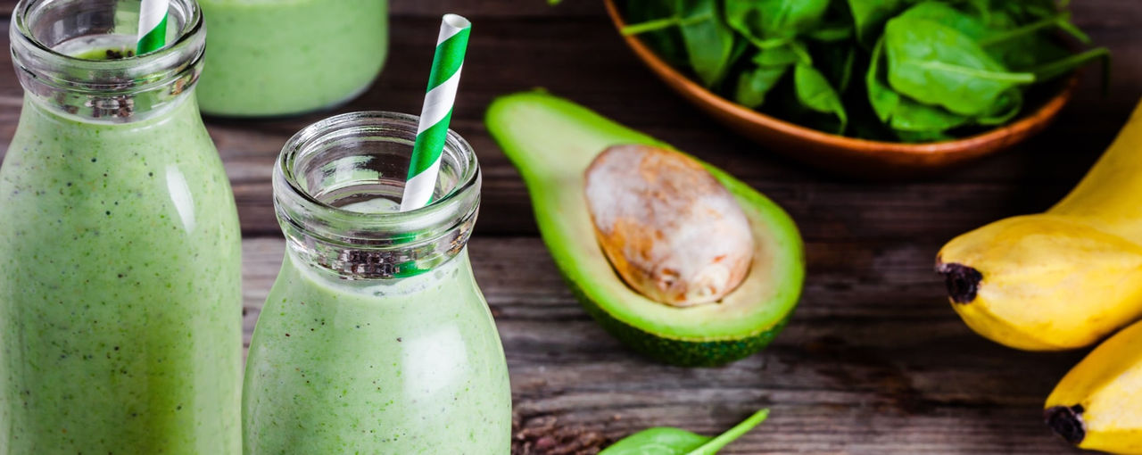 Green smoothies next to an avocado