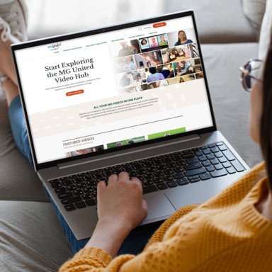 Woman scrolling through MG United Video Hub on laptop