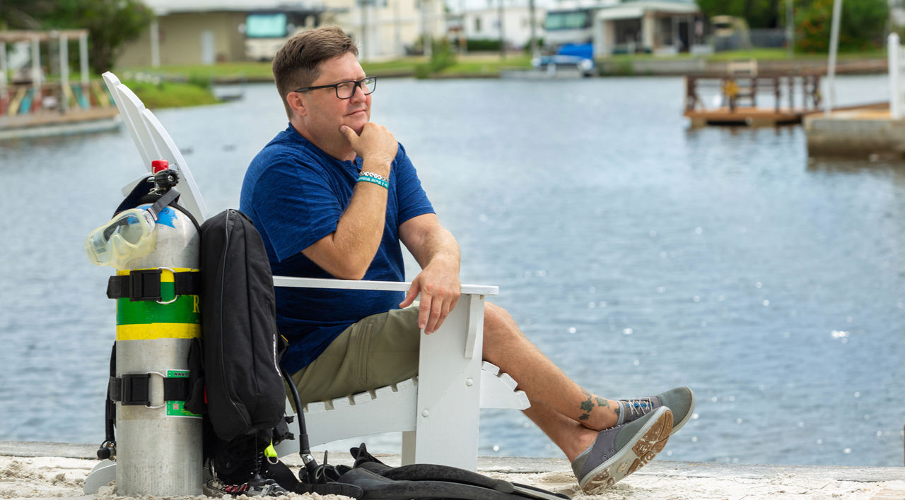 Chris sitting outside by a lake