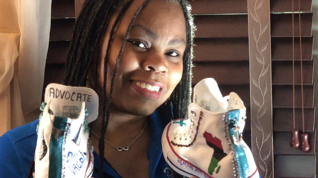 Dawn holding a pair of shoes she decorated